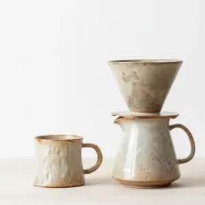 Handmade wood-fired porcelain V60 dripper with switch on white background